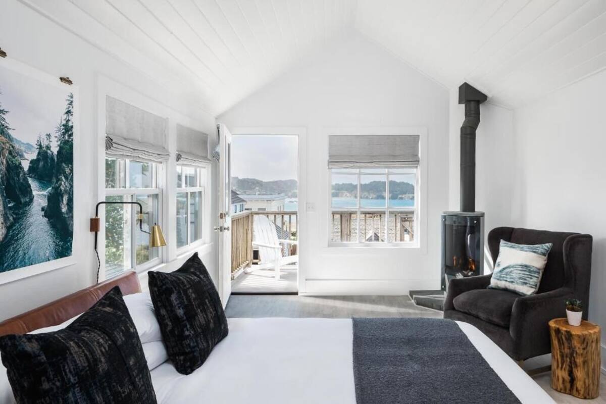 Un dormitorio con una cama grande, vista al mar, chimenea y terraza.
