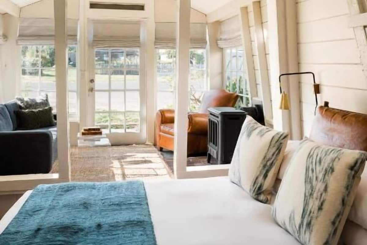 Una habitación amplia con una cama grande, una zona de estar con sofá y sillones, y una chimenea.