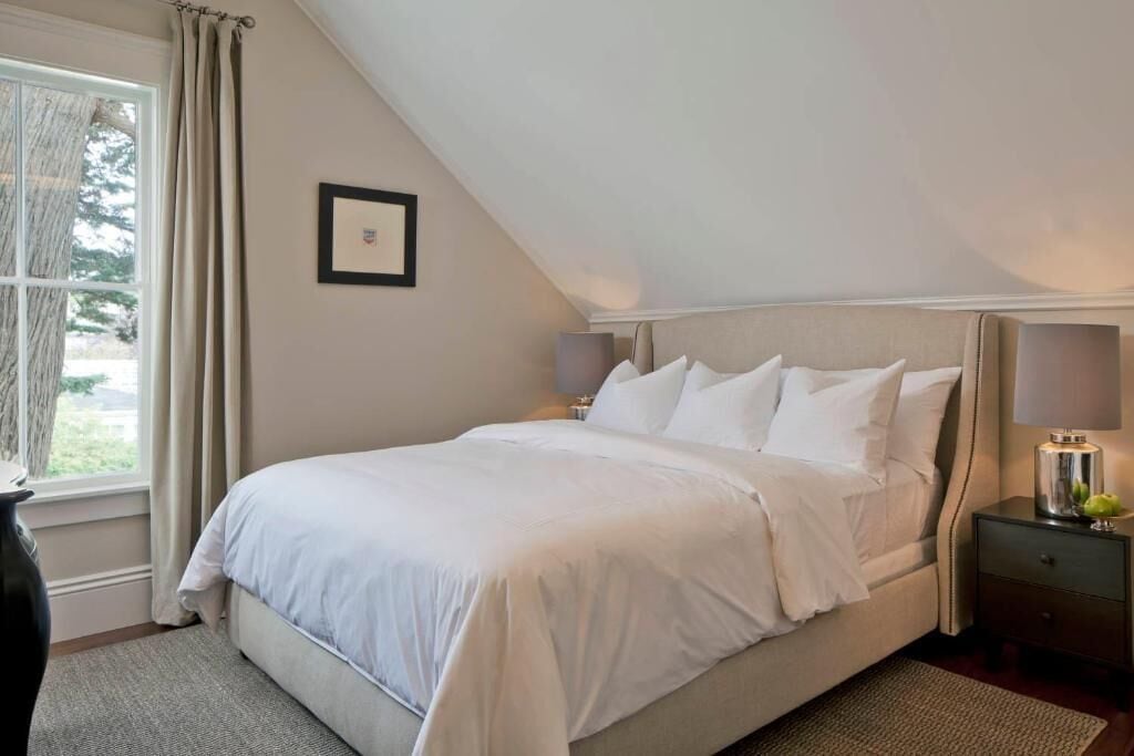 A bedroom with a bed, nightstands, a lamp, and a framed picture on the wall.