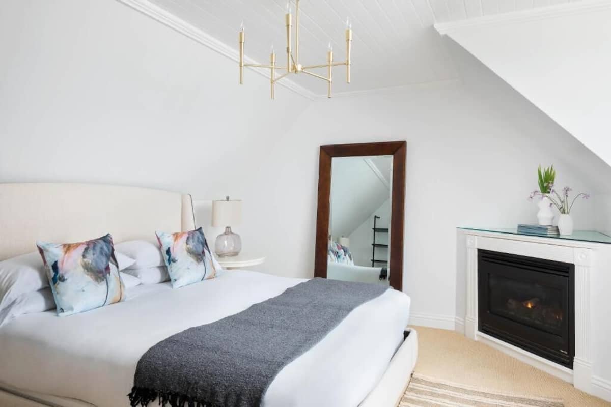 Un dormitorio con una cama grande, chimenea, candelabro y espejo.