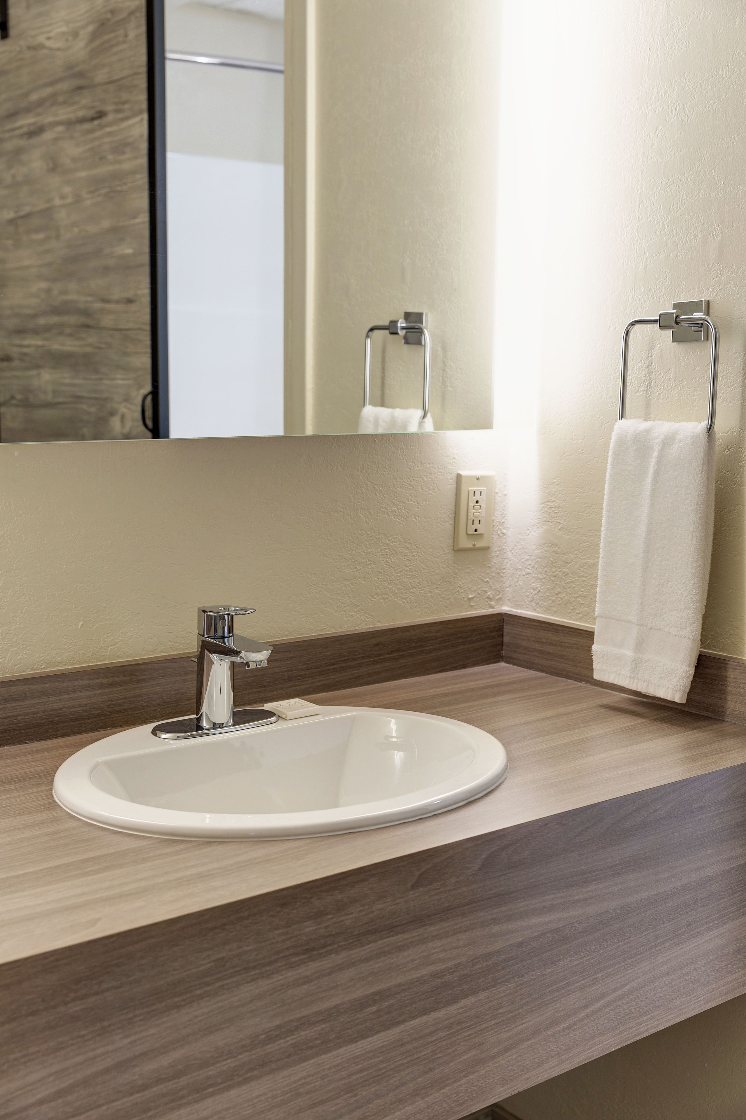 Ein modernes Badezimmer mit einem weißen Waschbecken, einem Chromarmaturen und einem Handtuchhalter.