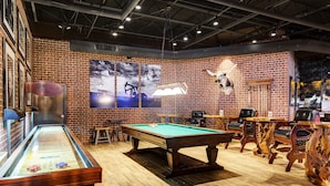 Una sala de billar con mesa de pool, sillas de madera y una vitrina de vidrio.