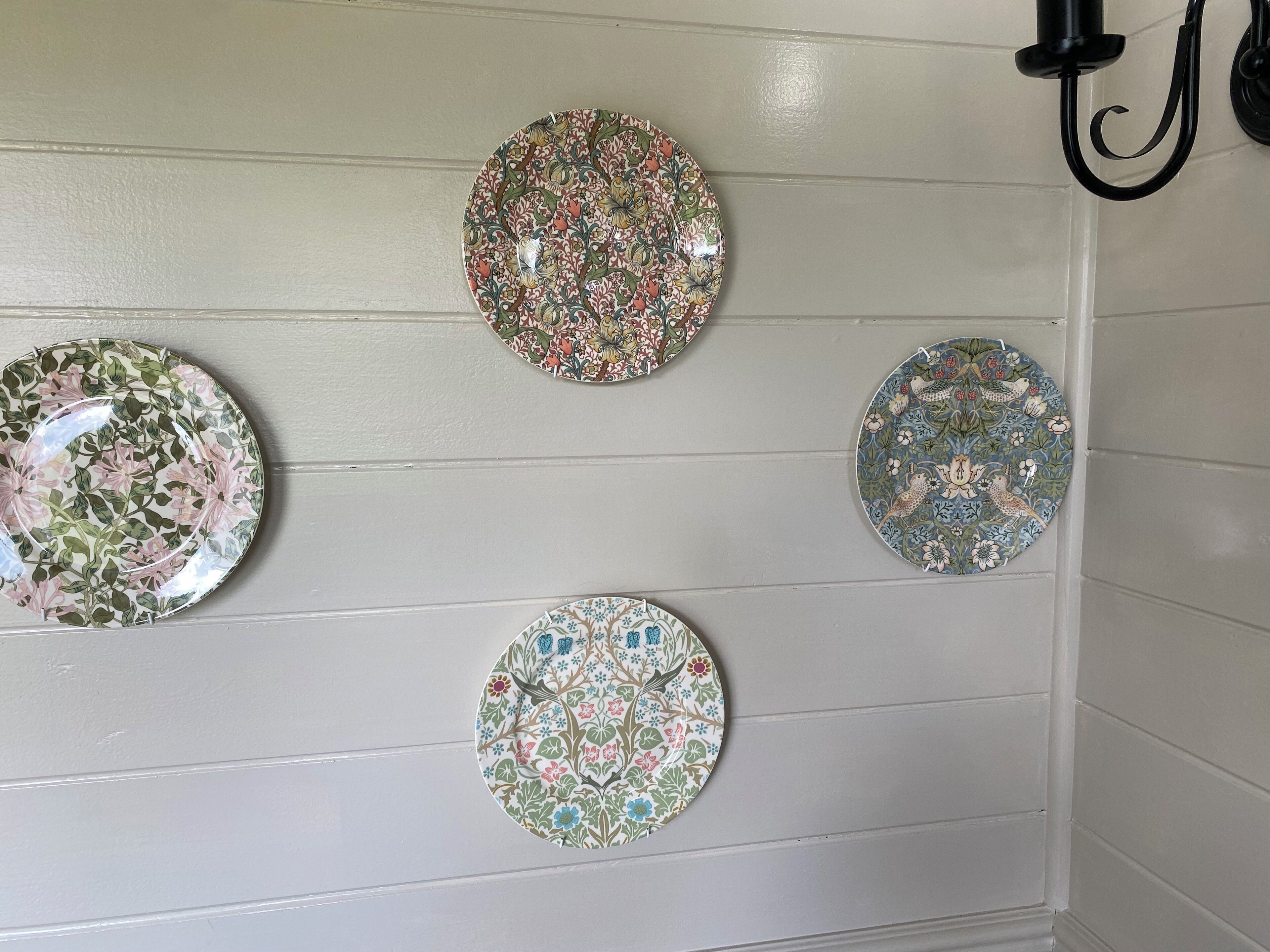 Quatre assiettes décoratives à motifs floraux, conçues pour être fixées au mur.