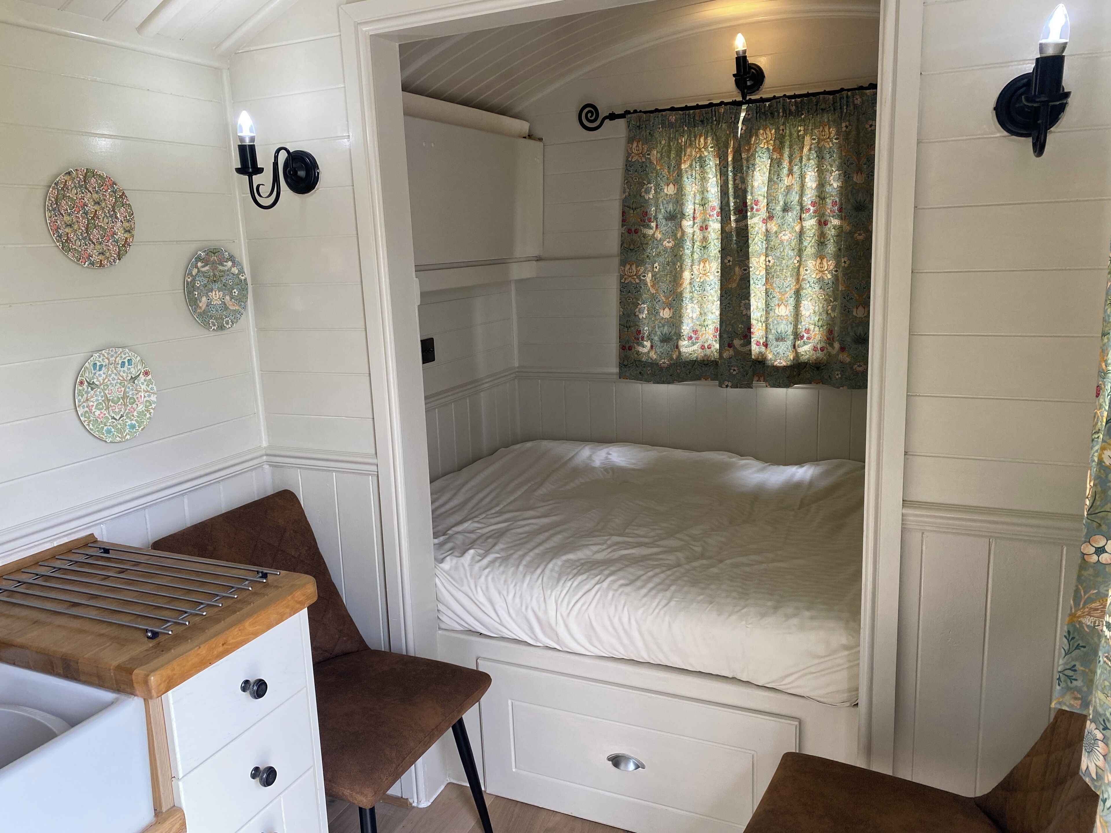 Ein Schlafzimmer mit einem Bett, einem Sessel, einem kleinen Tisch und dekorativen Tellern an der Wand.