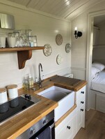 Une cuisine compacte dotée d’un plan de travail en bois, de meubles blancs et d’un évier encastré.