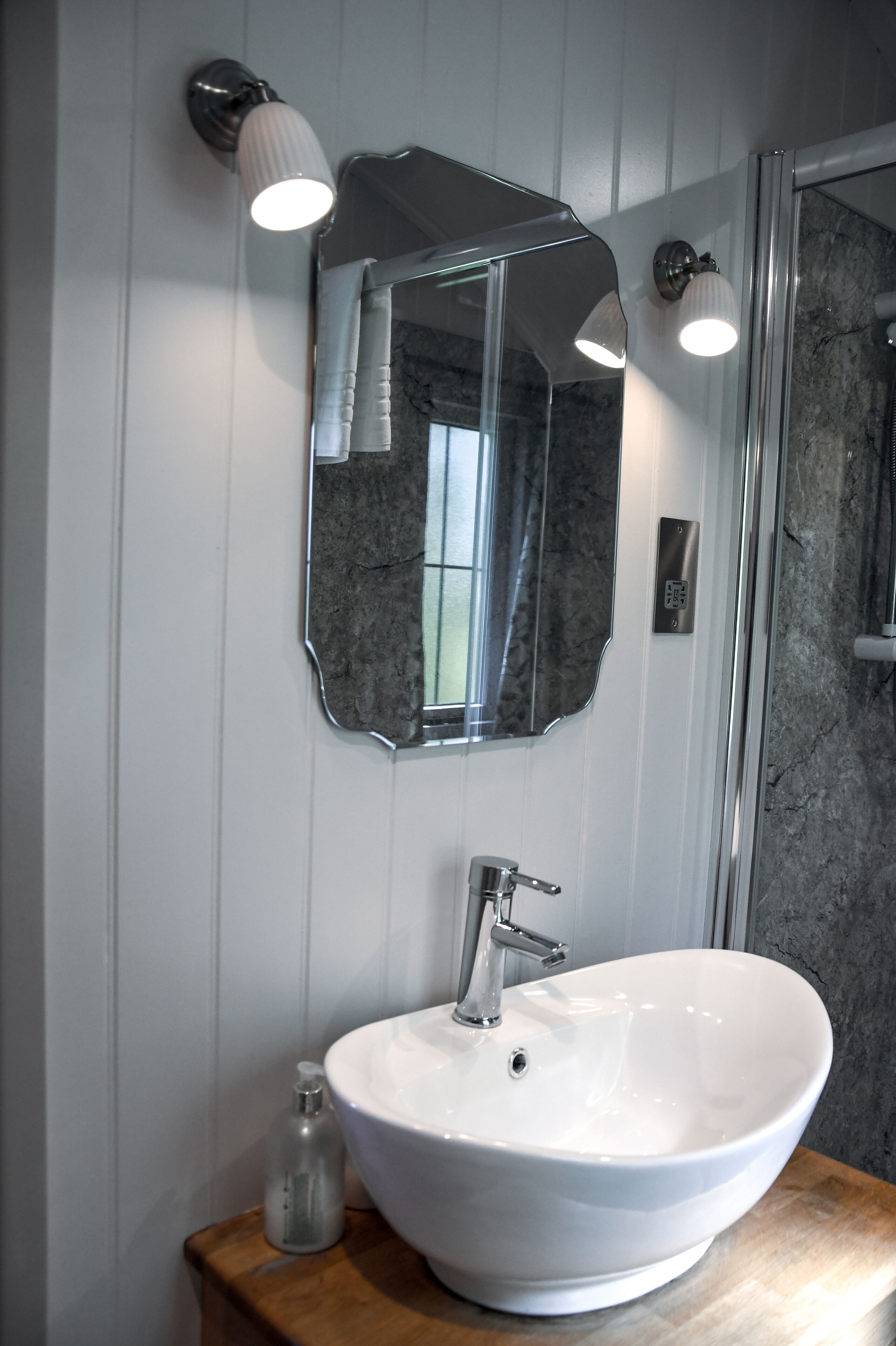 A bathroom with a white sink, a mirror, and a shower.