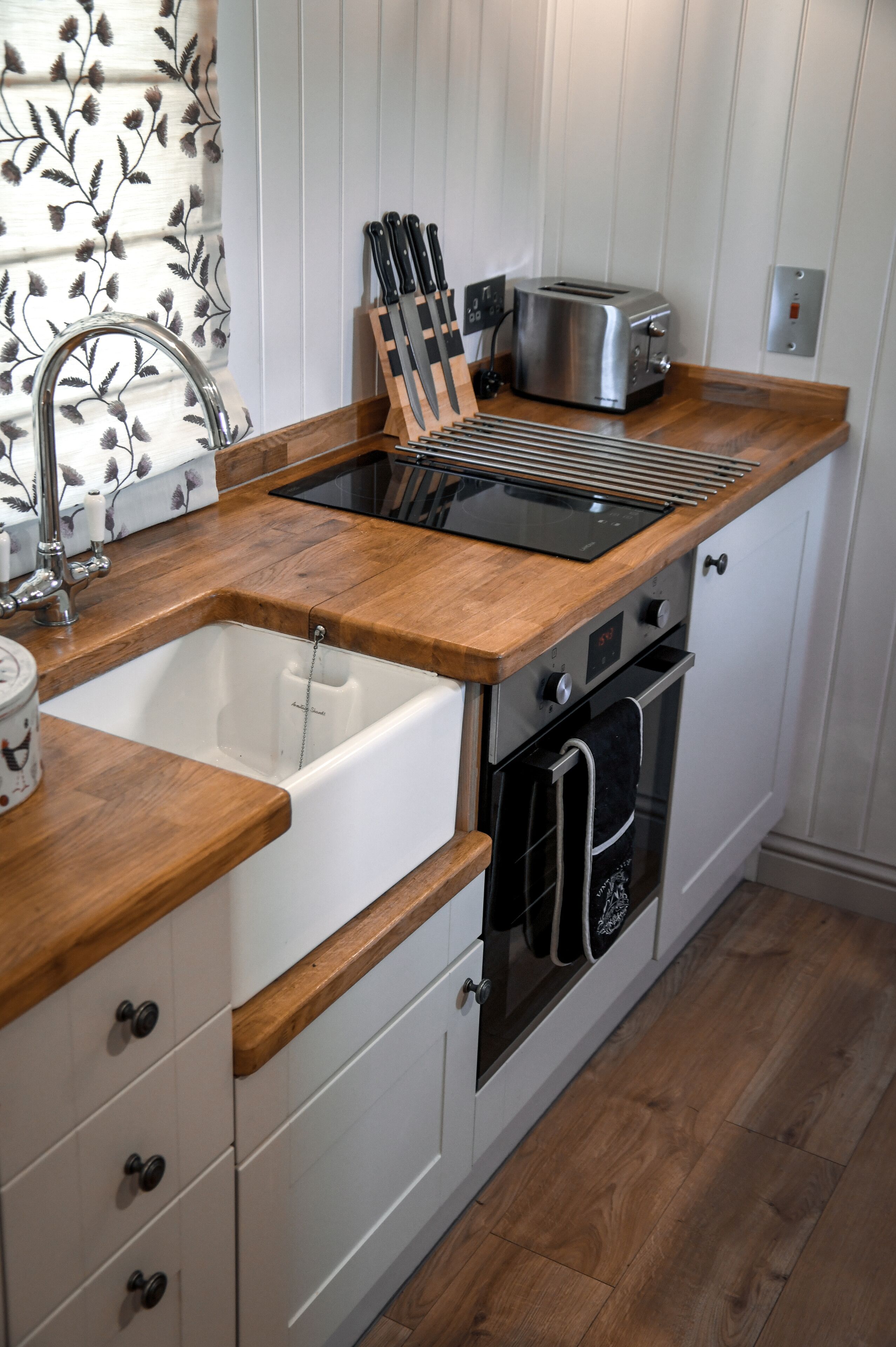A kitchen with wooden countertops, a built-in sink, a toaster, and an oven.