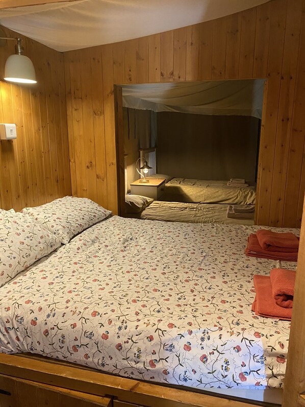 Una habitación con paneles de madera, una cama con ropa de cama floral y un dosel.