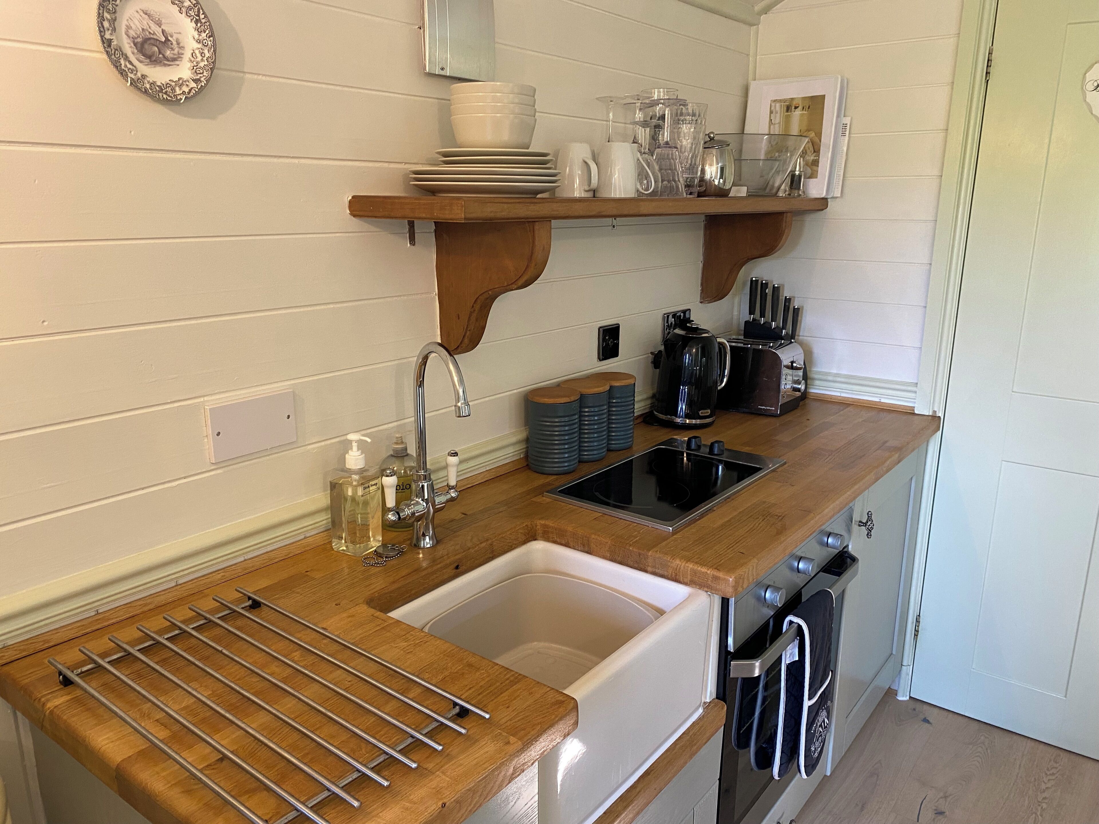 A compact kitchen with a wooden countertop, a sink, a stove, and a coffee maker.