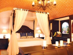 A four-poster canopy bed with white drapes, a wooden headboard, and two bedside lamps. - Casona María (Puebla)
