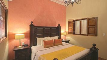 Quarto de hotel com uma cama grande, duas mesas de cabeceira com luminárias, um painel de cama de madeira e uma janela com cortinas.