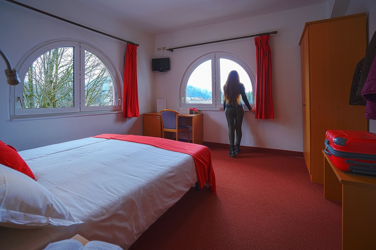 Een kamer met een bed, een bureau en een kledingkast.