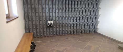 A room with a tiled floor, a bench, a shoe rack, and a window.