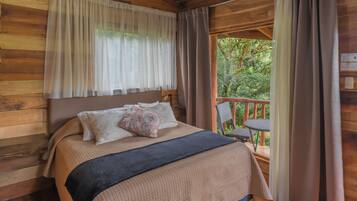 Un dormitorio de cabaña de madera con una cama, una mesita de noche y vistas al exterior.