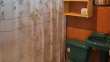 Une salle de bain équipée de toilettes, d’un lavabo et d’étagères où sont rangées les serviettes.