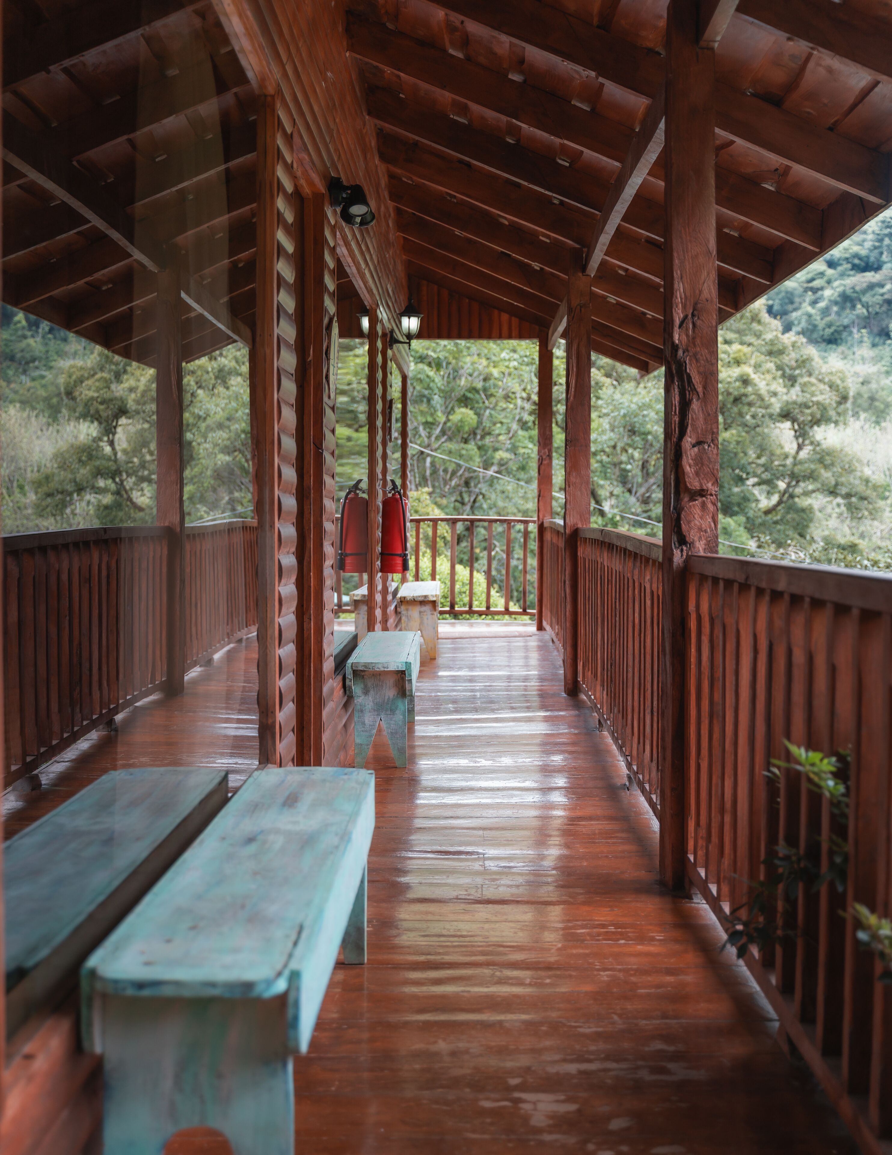A wooden deck with benches and lanterns, overlooking a forested area.