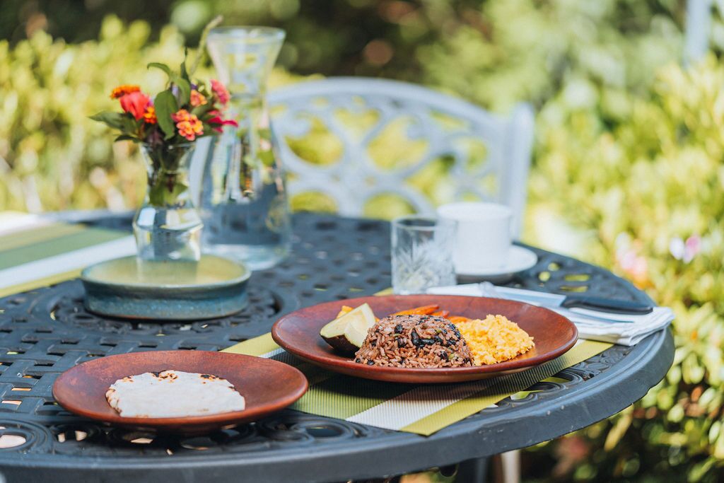 A dining table with plates of food, a vase with flowers, and a glass of water.