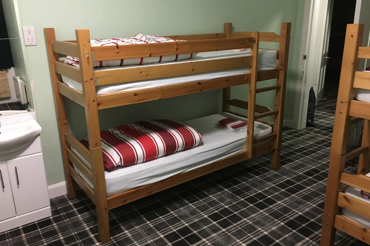 A bunk bed with a checkered floor, a sink, and a door in the background.