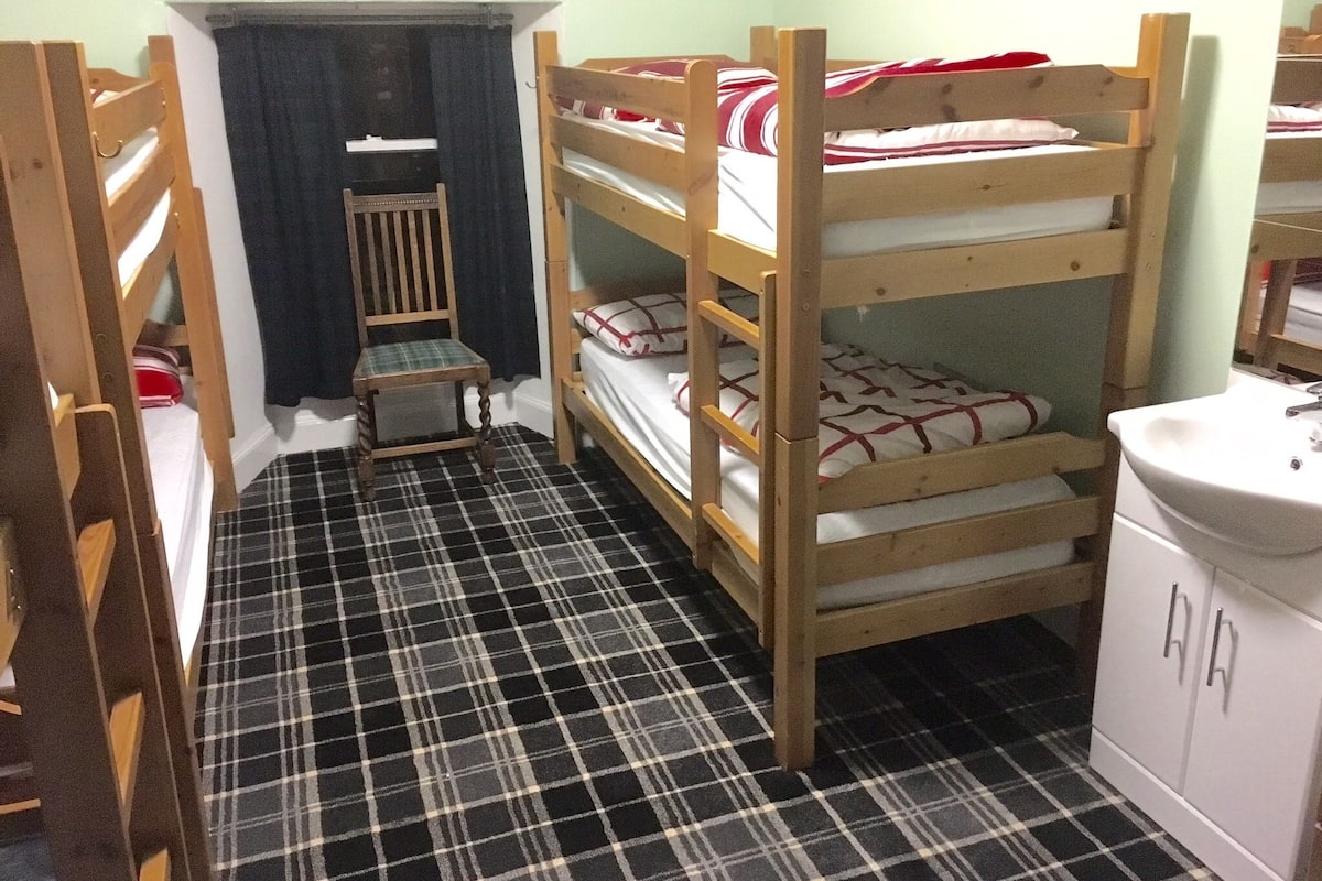 A bunk bed room with a checkered floor, a small wooden chair, and a white cabinet with drawers.