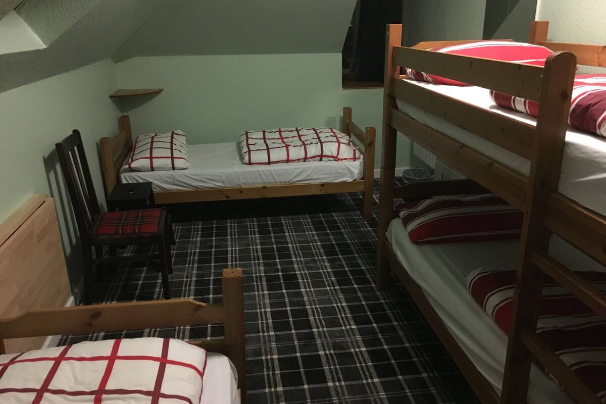 A dormitory room with bunk beds, a small desk, and a chair.