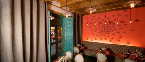 Un restaurante con vigas de madera en el techo, una puerta azul turquesa y una pared decorada con motivos de peces.