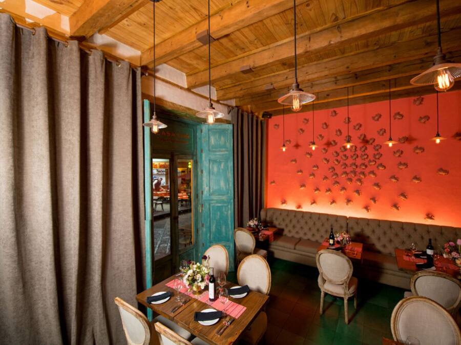 A restaurant with wooden ceiling beams, a teal door, and a wall with fish decorations.