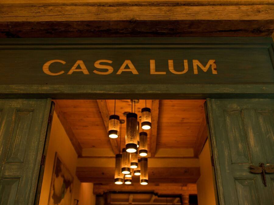 Une porte en bois sur laquelle est apposée une enseigne indiquant « CASA LUM », signalant l’entrée d’une propriété.