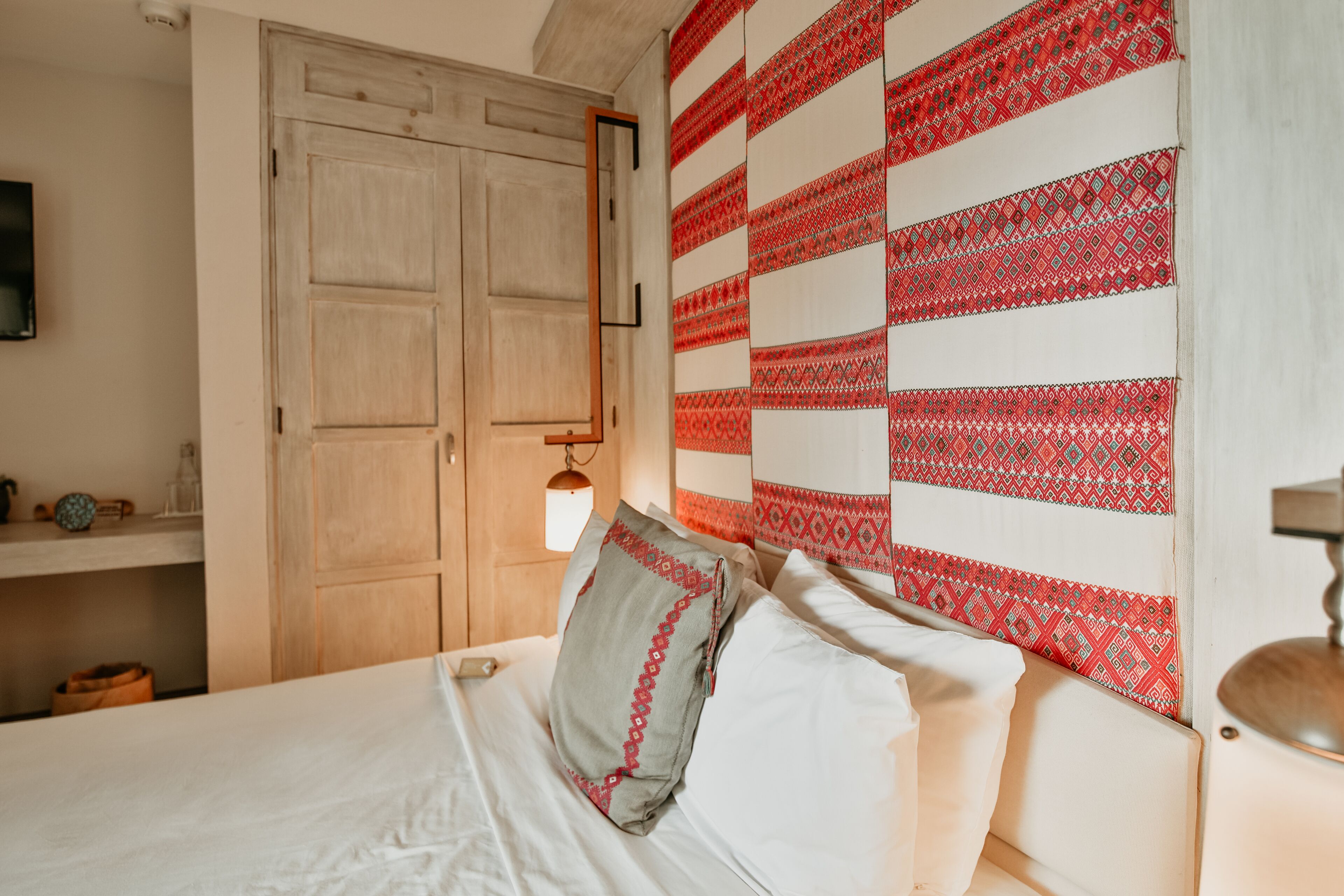 A bedroom with a bed, a wardrobe, and a patterned wall.