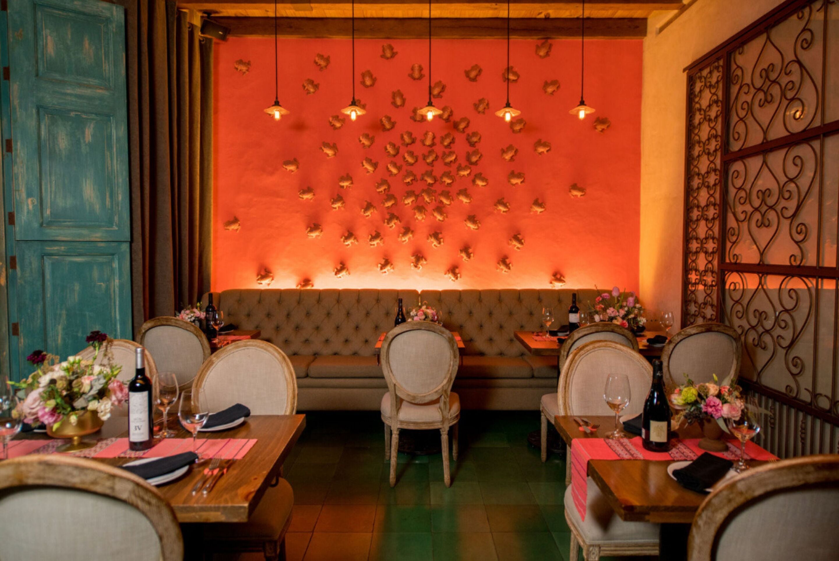 A restaurant interior with a red wall, wooden furniture, and hanging lights.
