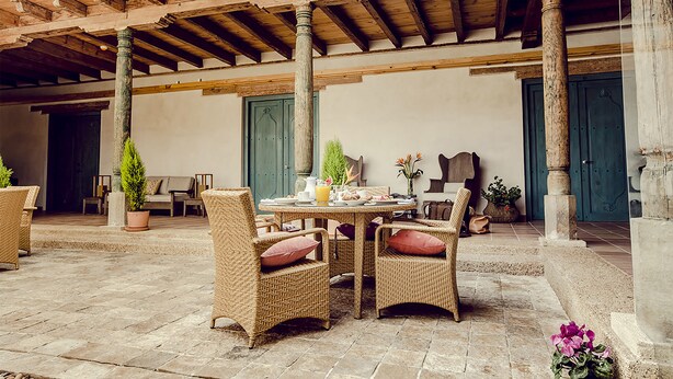 Un patio al aire libre con mobiliario de mimbre y una mesa lista para comer.
