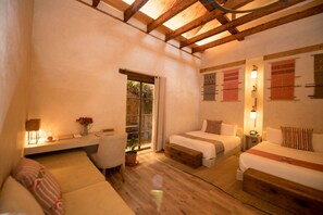 A cozy room with a wooden ceiling, a sofa, two beds, a desk with a lamp, and a window with curtains. - Casa Lum (San Cristóbal de las Casas)
