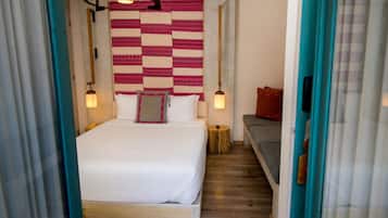 Un dormitorio con una cama, lámparas de noche, una mesita redonda y un sofá.