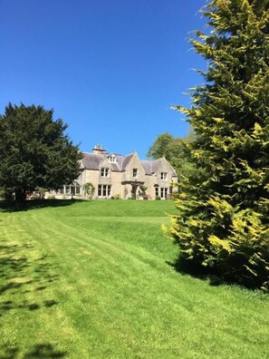 A large, historic building with a well-maintained lawn and mature trees. - Whitchester Christian Guest House (Hawick)