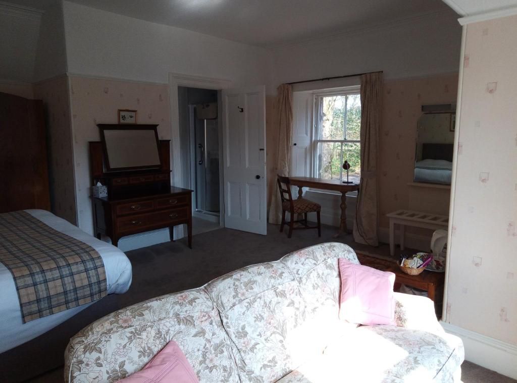Een slaapkamer met een bed, een dressoir, een bureau en een stoel.