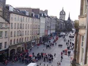 Een levendig stadsplein met historische gebouwen, een opvallende kerktoren en een rode telefooncel.