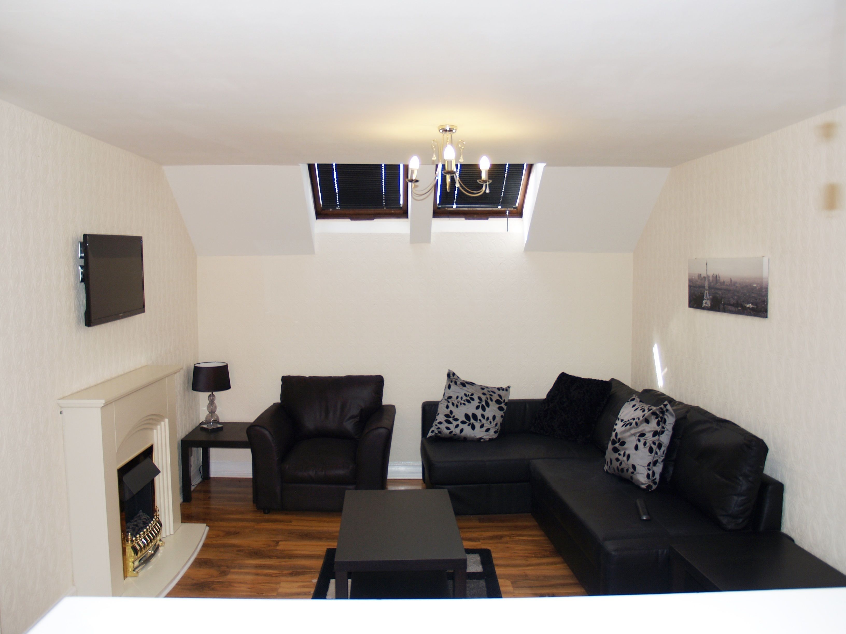 A living room with a fireplace, a sofa set, a coffee table, and a TV mounted on the wall.