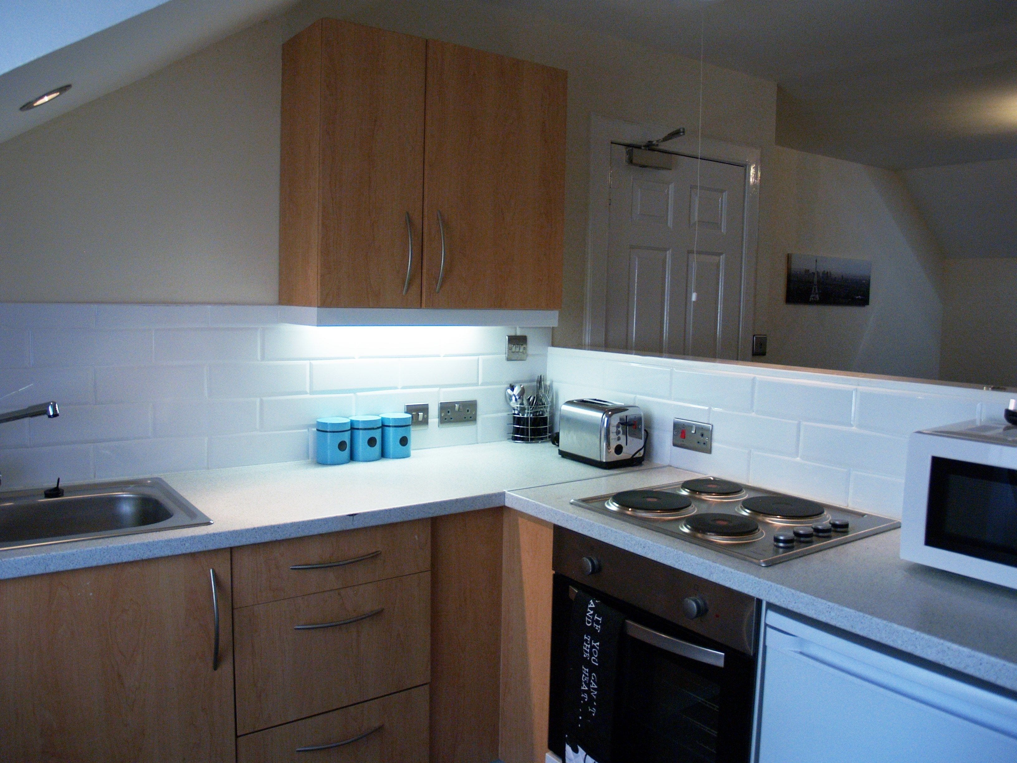 A modern kitchen with wooden cabinets, a stainless steel sink, a toaster, a microwave, and an oven.