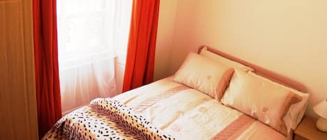 Un dormitorio con cama, almohadas, mesita de noche y armario.