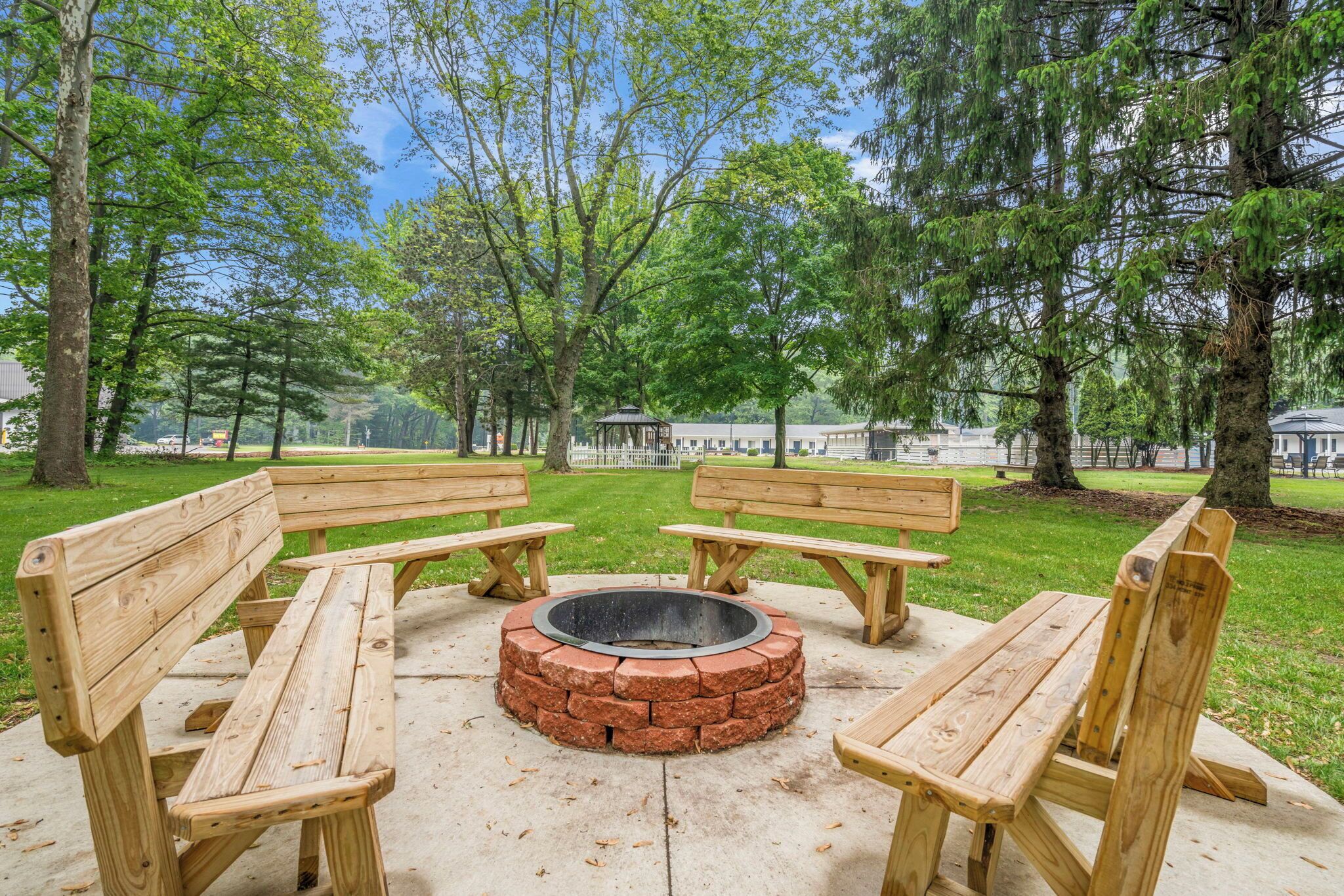 Un parco con panchine in legno e un braciere circolare.