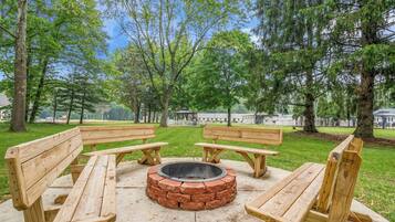 Un parque con bancos de madera y un brasero circular.