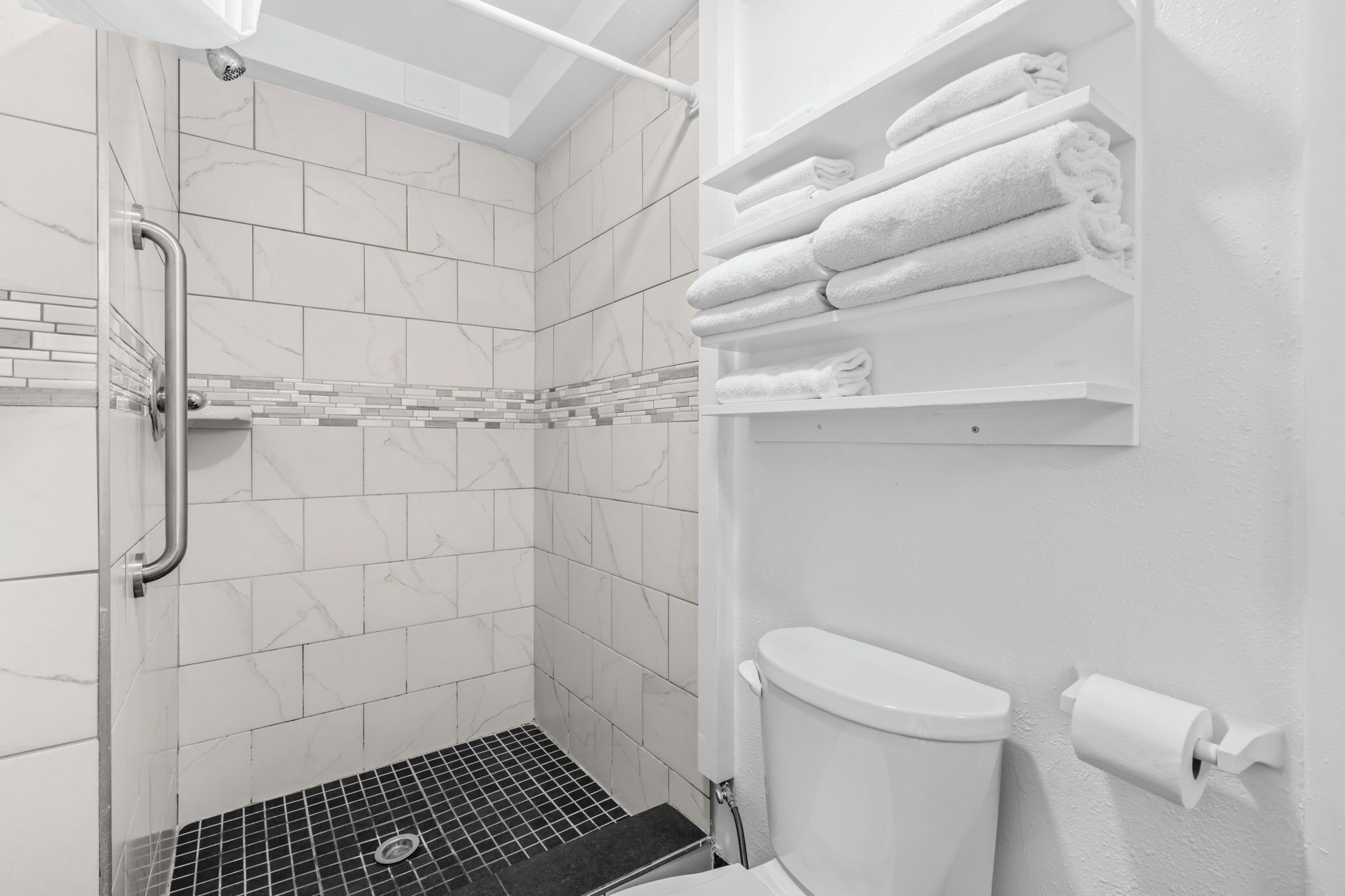 A bathroom with a shower, toilet, and towel rack.