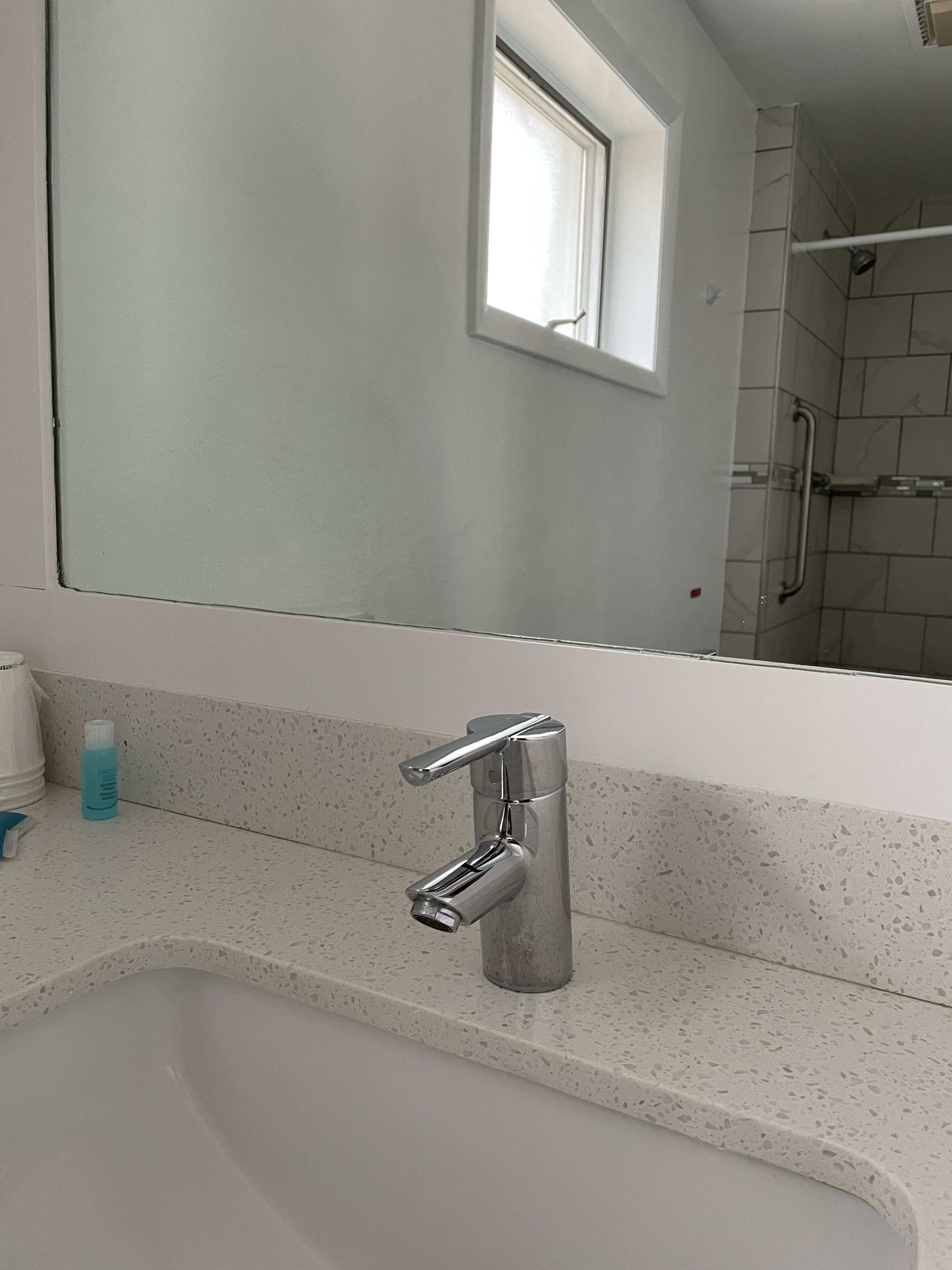 Een badkamer met een wit wastafel, een chromen kraan en een spiegel erboven.