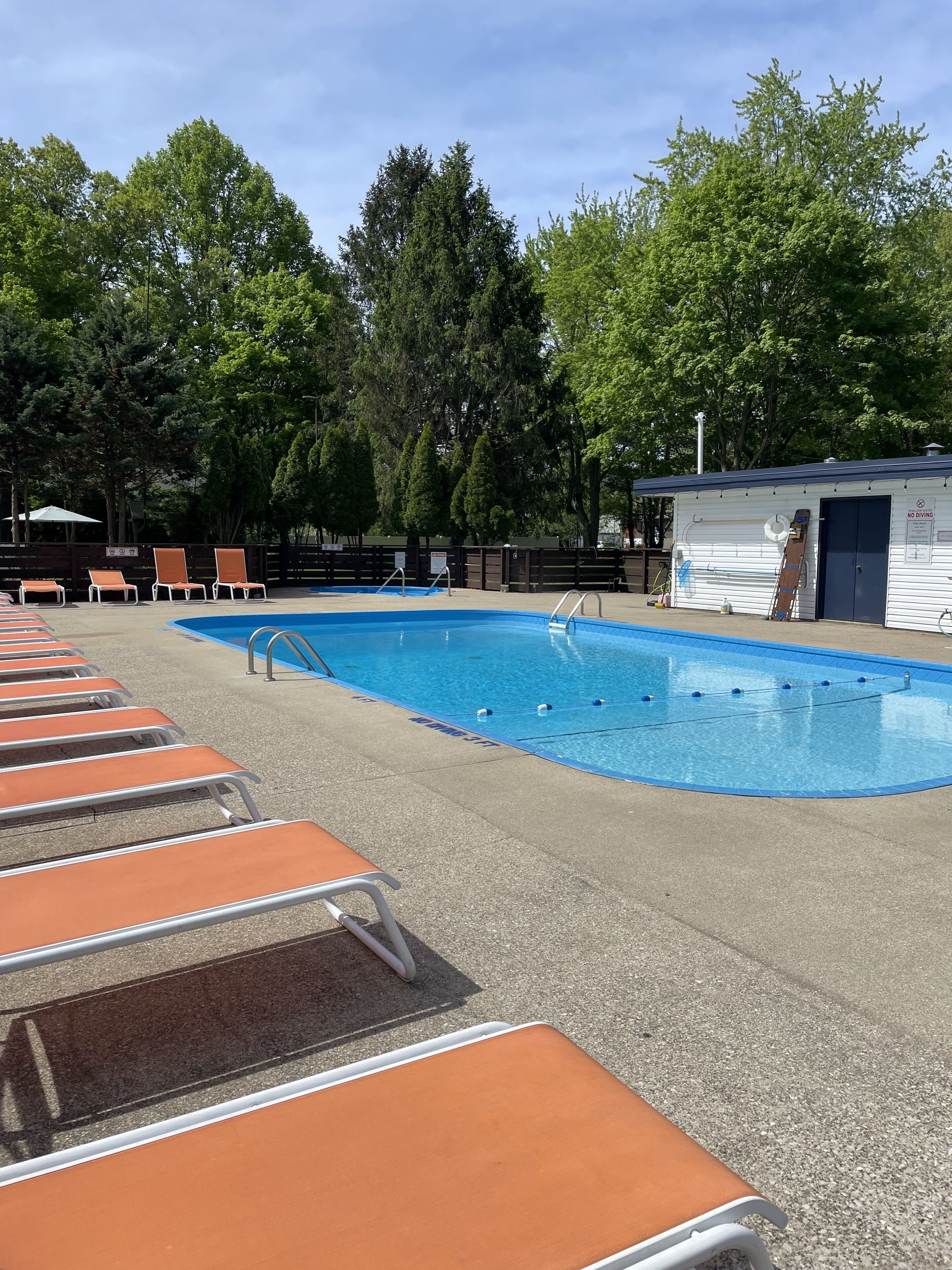 Ein Swimmingpool mit Liegestühlen und ein kleines Gebäude mit einem Schild 'NO DIVING'.