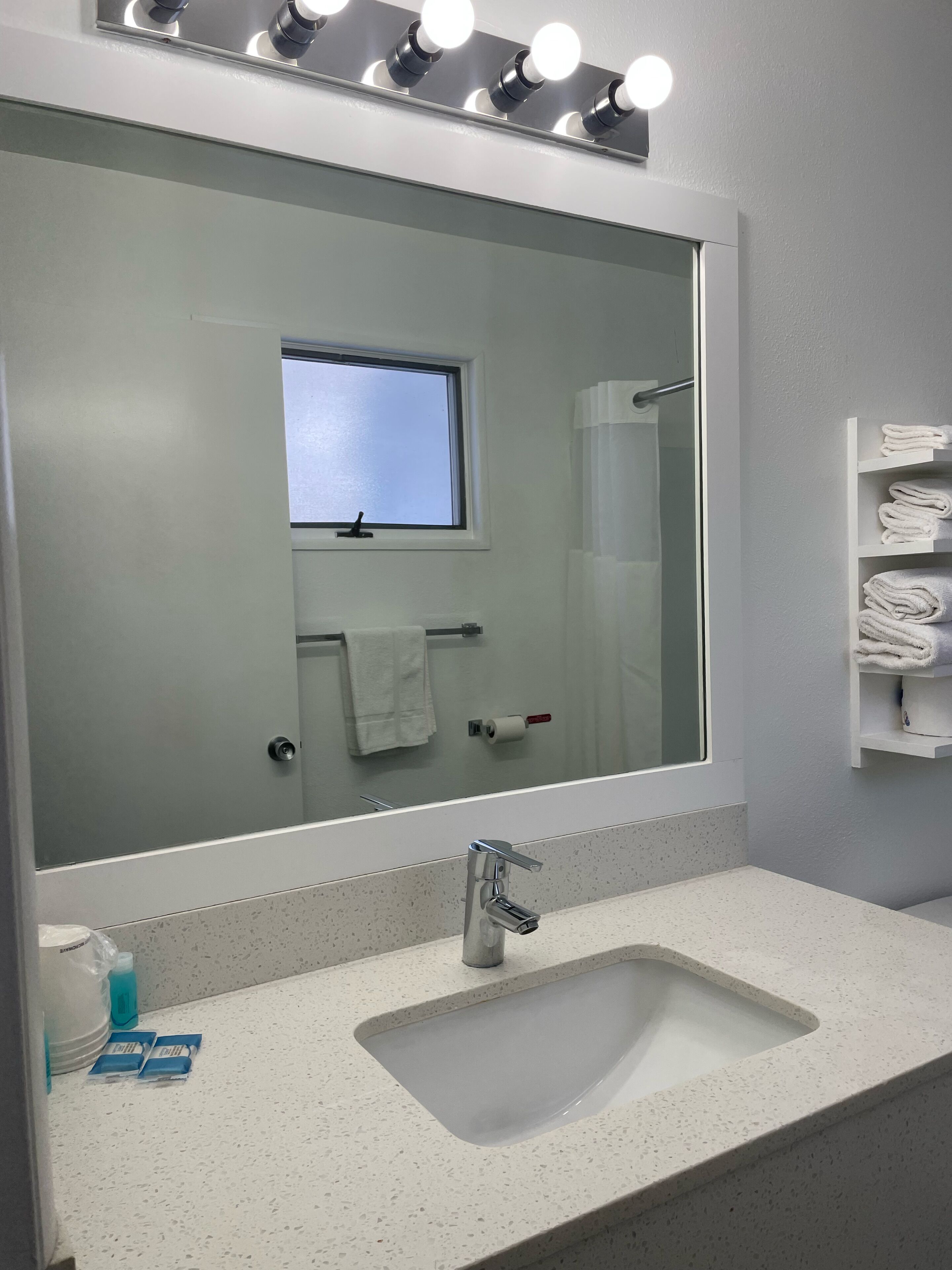 Un bagno con uno specchio grande, un lavandino e un porta asciugamani.