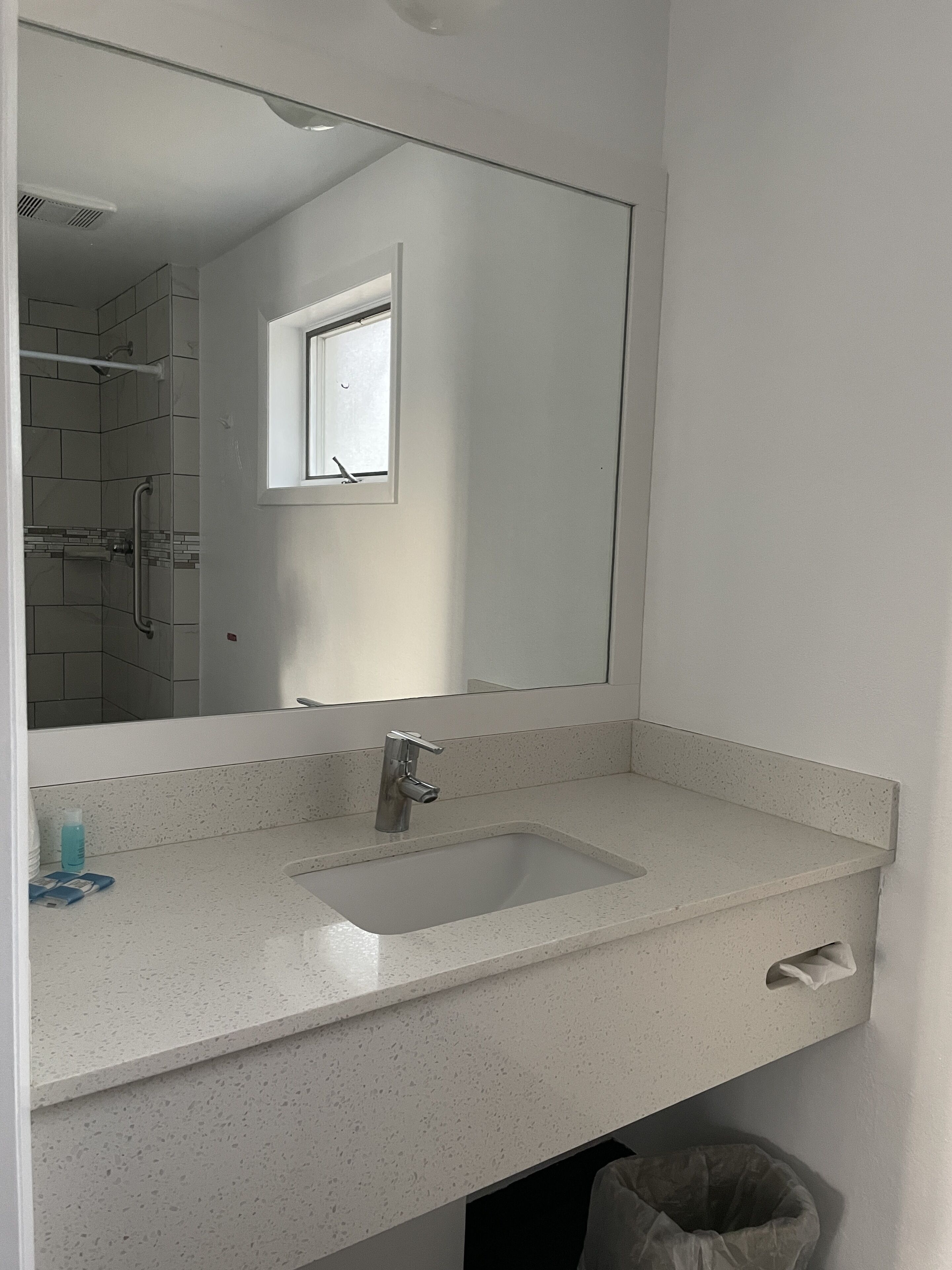A bathroom with a white sink, a mirror, and a window.