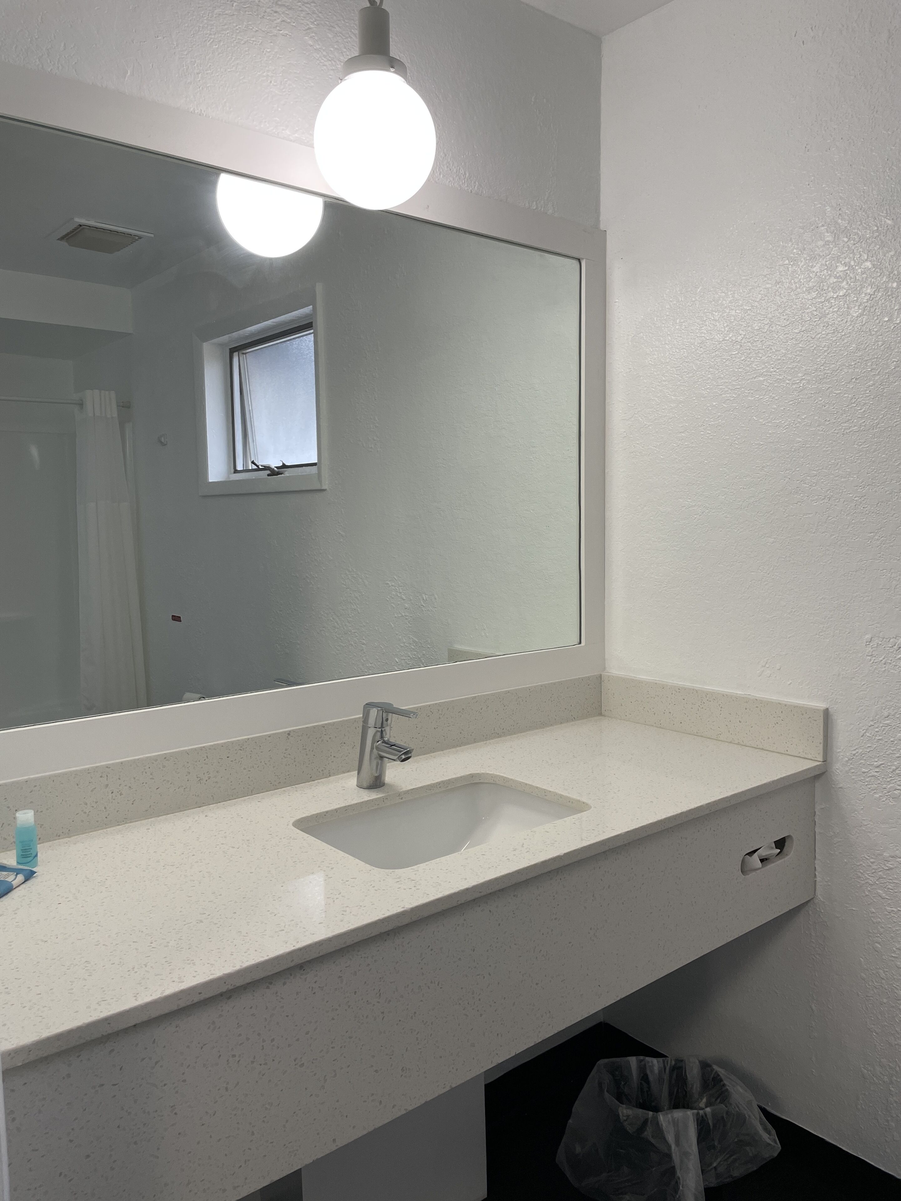 A bathroom with a white sink, a mirror, and a window.