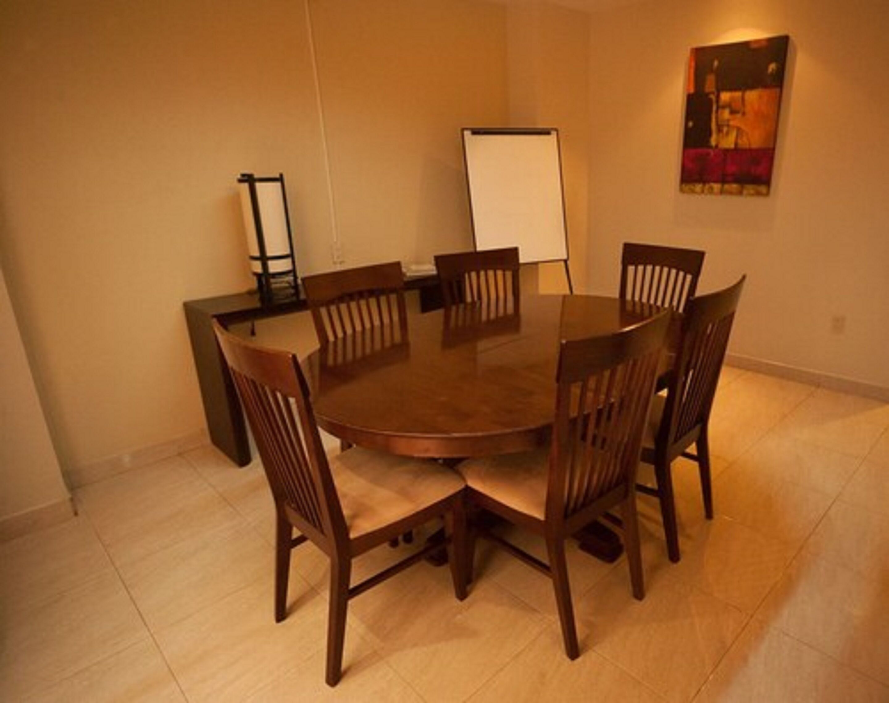 Un salón de conferencias con una mesa redonda y seis sillas de madera.