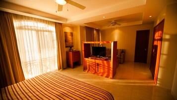 A hotel room with a bed, a desk, a television, and a ceiling fan.