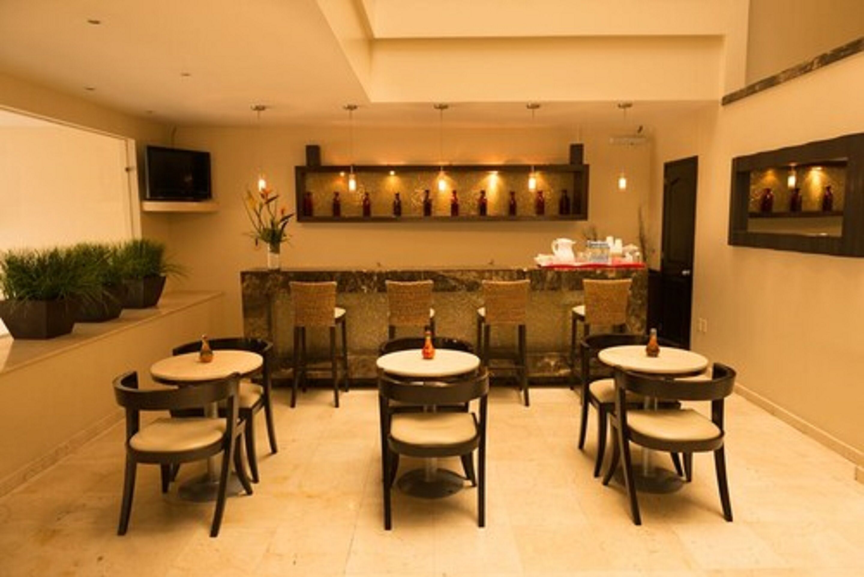 A restaurant with round tables and chairs, a bar area, and a television mounted on the wall.