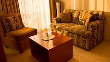 Suite, 1 cama King size | Área de sala de estar | Televisión de pantalla plana